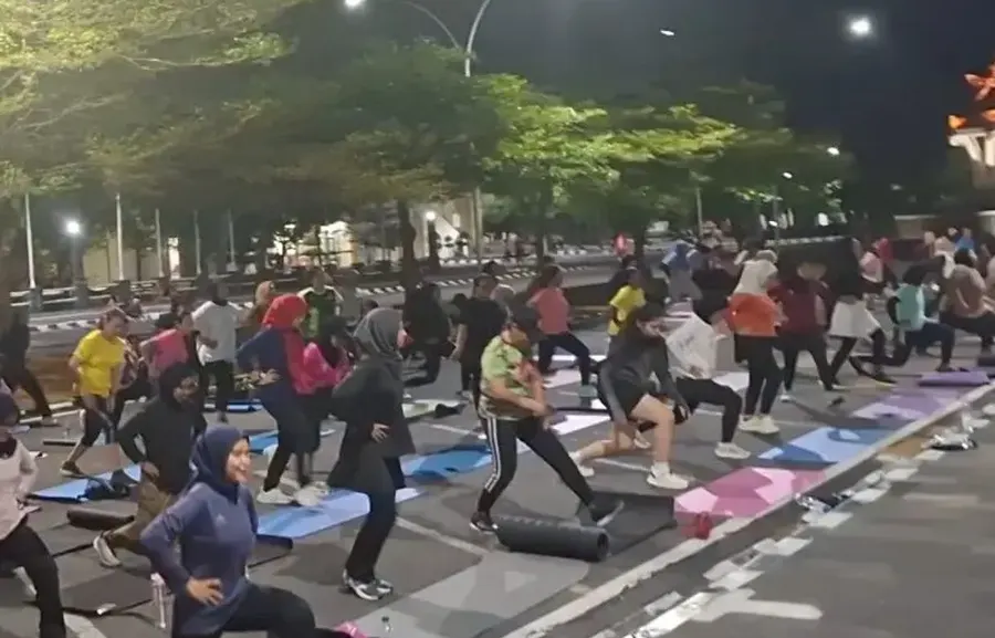 Peserta latihan bersama di ruang terbuka pada malam hari